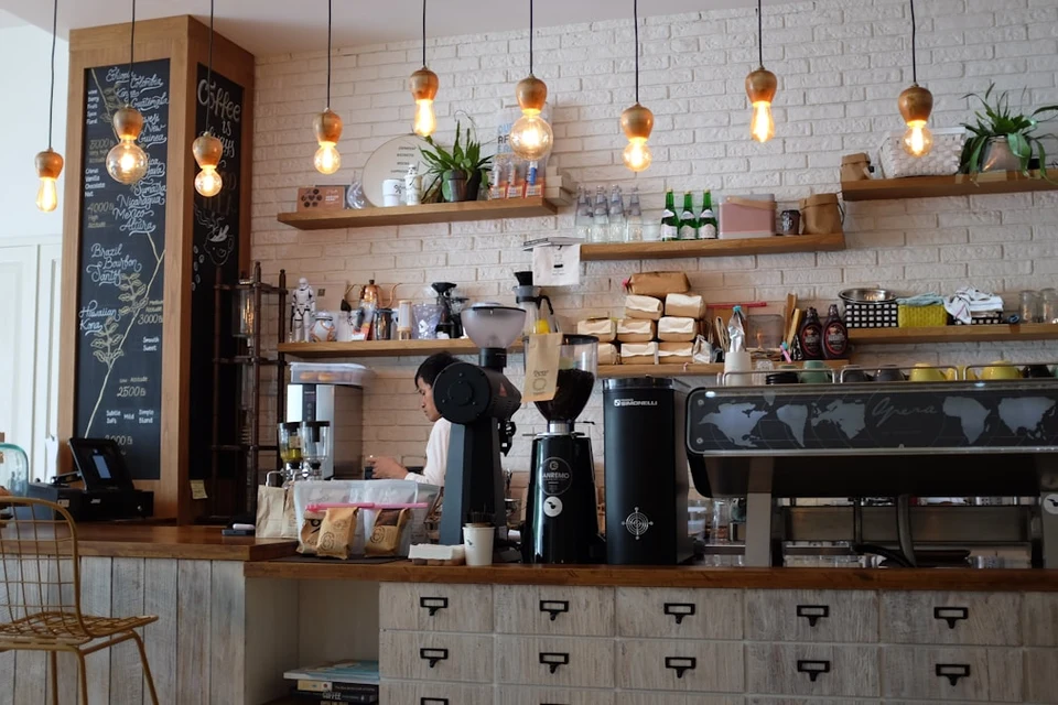Café interior with pale brick, timber shelves, plants and warm pendant lights