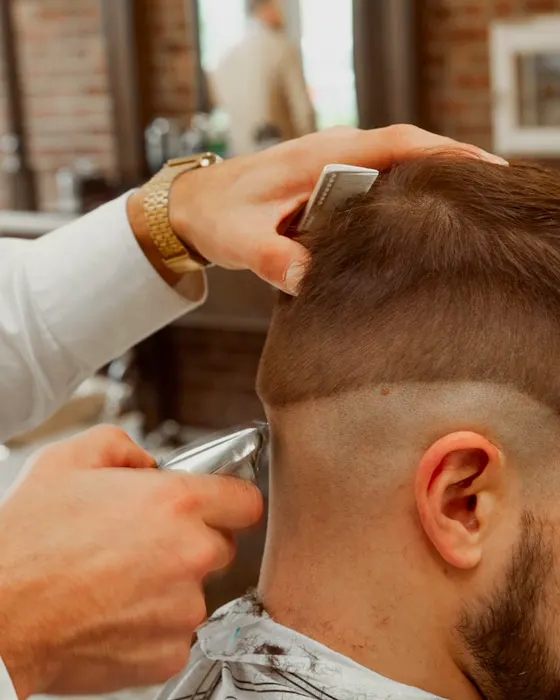 Marek shaping the back of a client's head with clippers