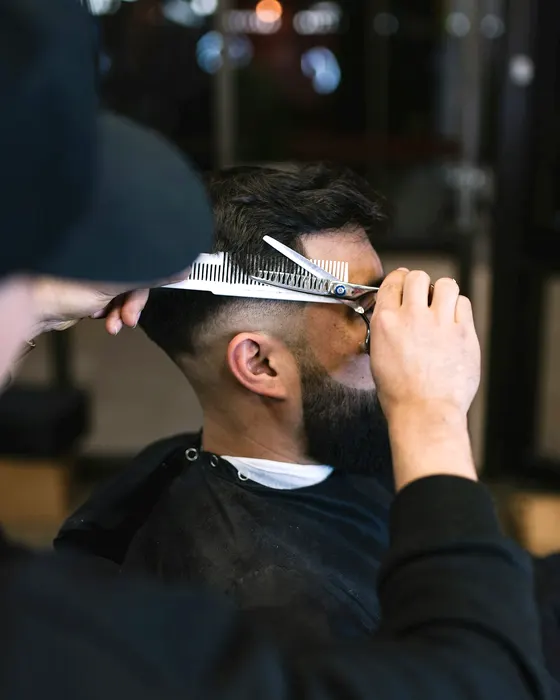 Dele cutting over a comb with scissors