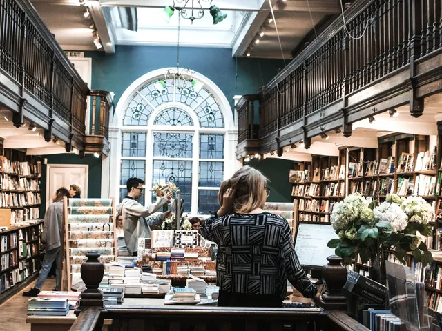 The front room on a busy Saturday: customers browsing around the centre table, galleried shelves rising on both sides
