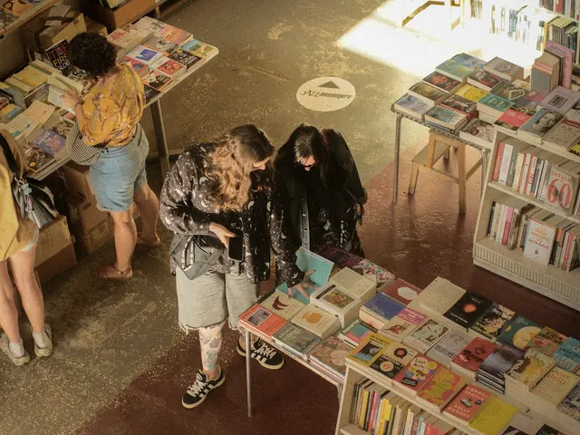 Customers reading covers at the browsing tables, sun coming in across the floor