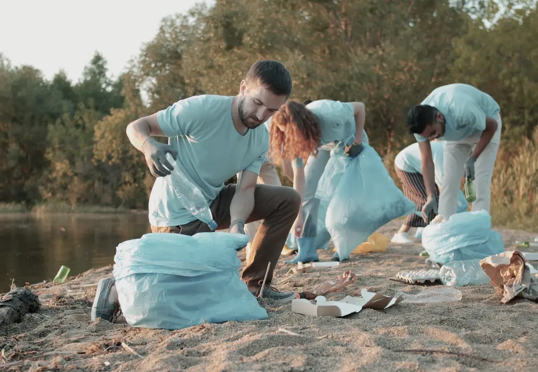Volunteers with sacks clearing litter from a riverbank
