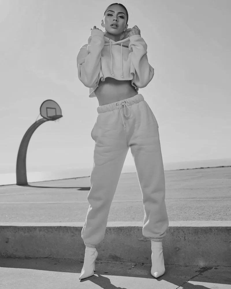 Model in a hooded track set beside an outdoor basketball court