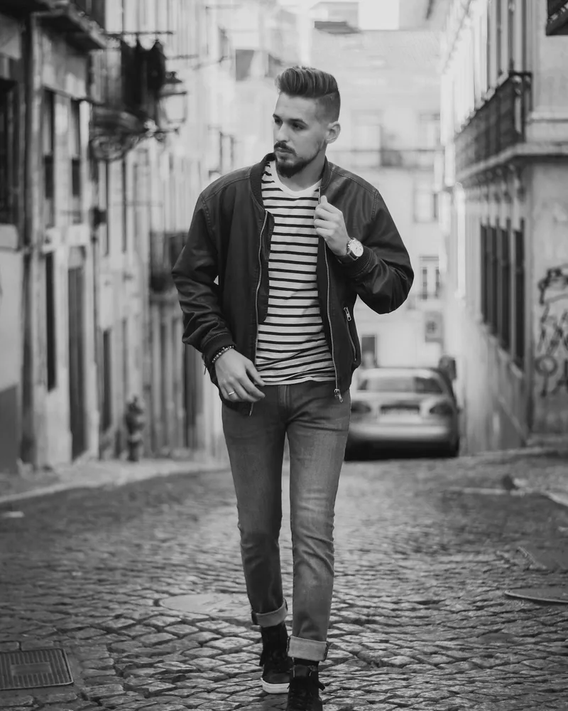 Model walking a narrow cobbled street in a bomber jacket