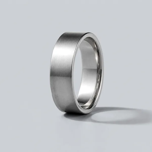 A wide platinum band with a brushed finish, standing on a pale surface.