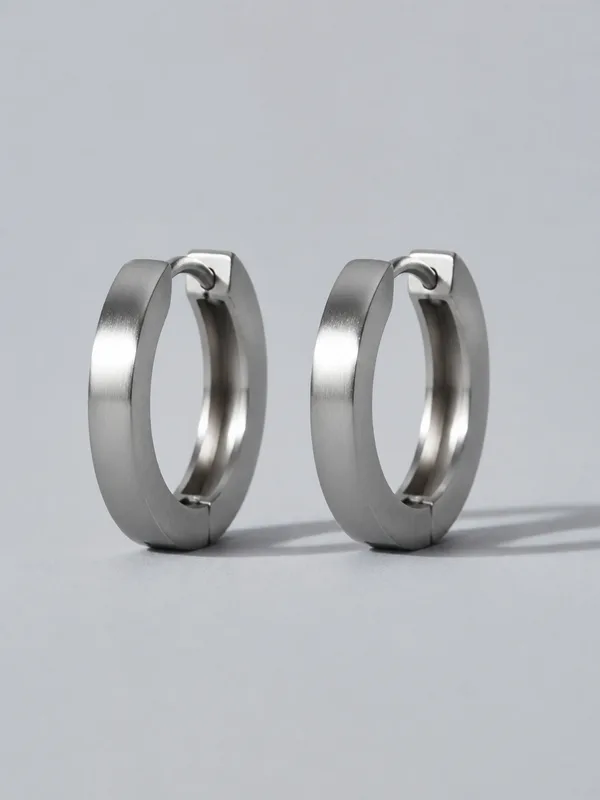 A pair of chunky platinum hoop earrings standing upright.