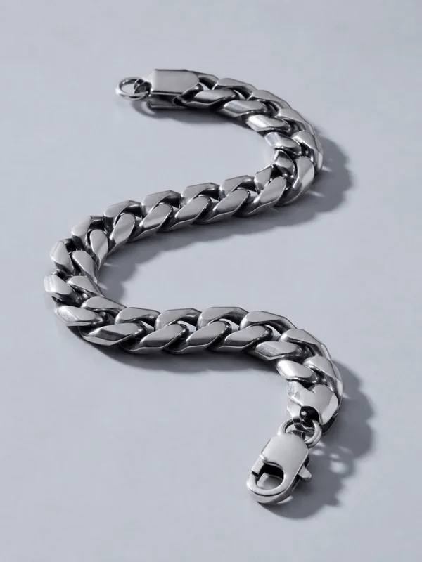A heavy platinum curb chain bracelet laid in an open curve.