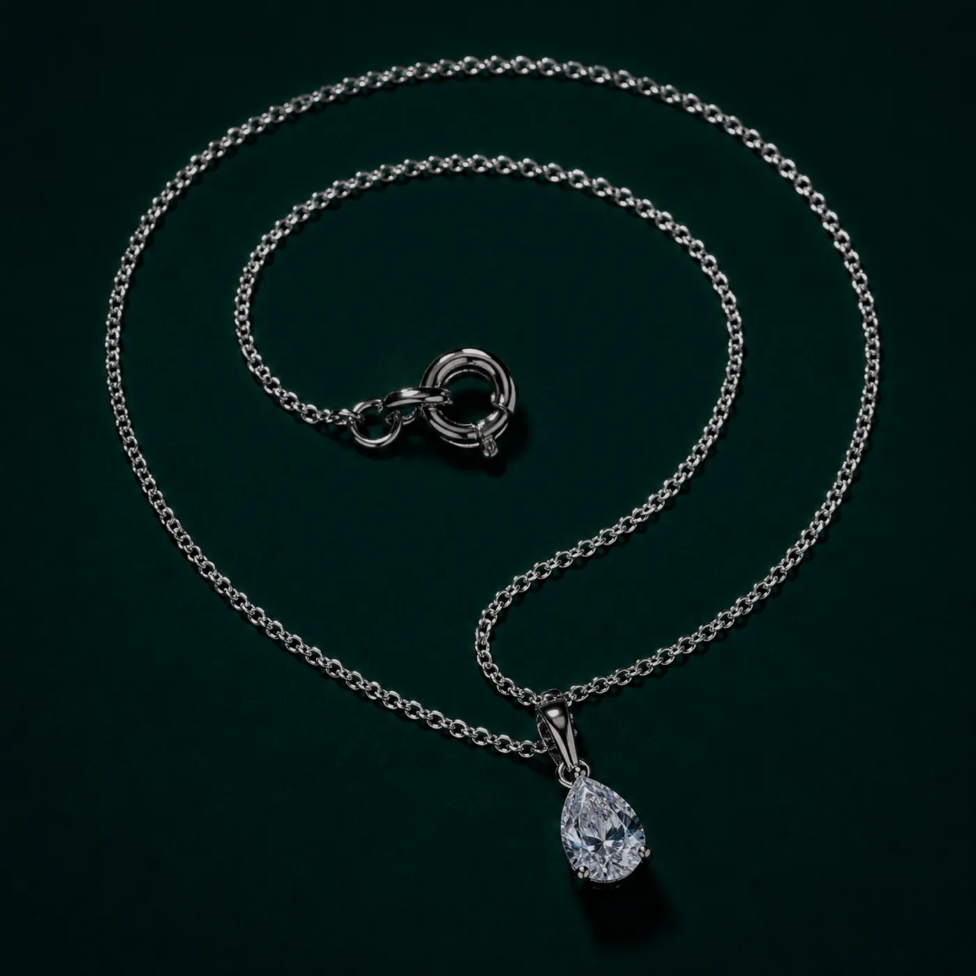 A platinum pendant on a fine chain, coiled and lit from one side against a dark ground.