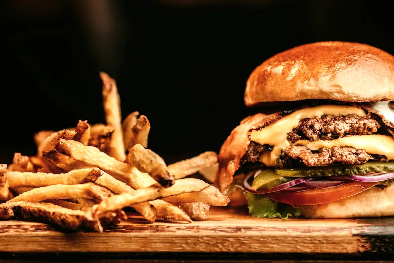 A burger and skin-on fries served on a wooden board