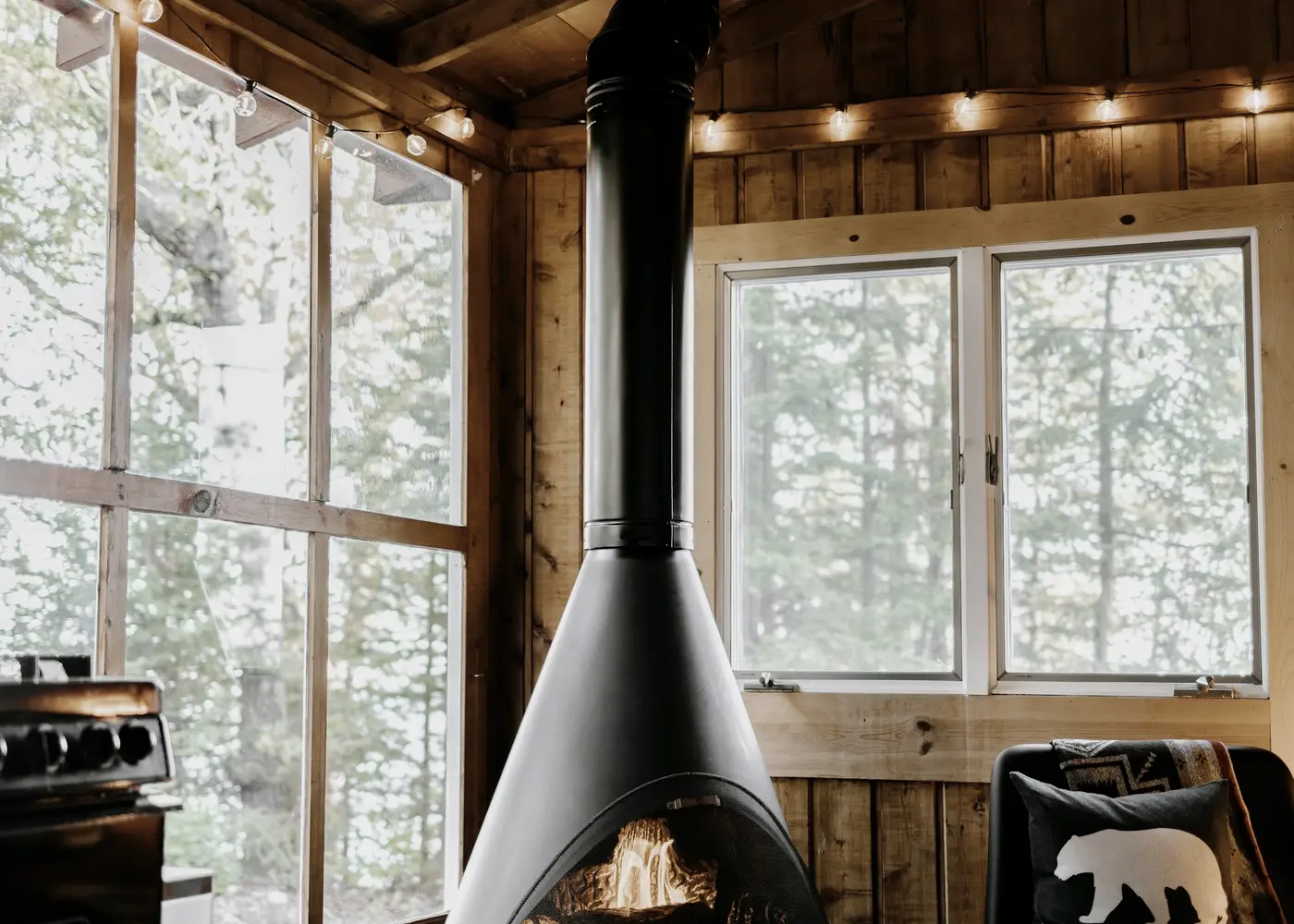 The stove and the long window in the living room at Hollowbeck, looking out into birch trees