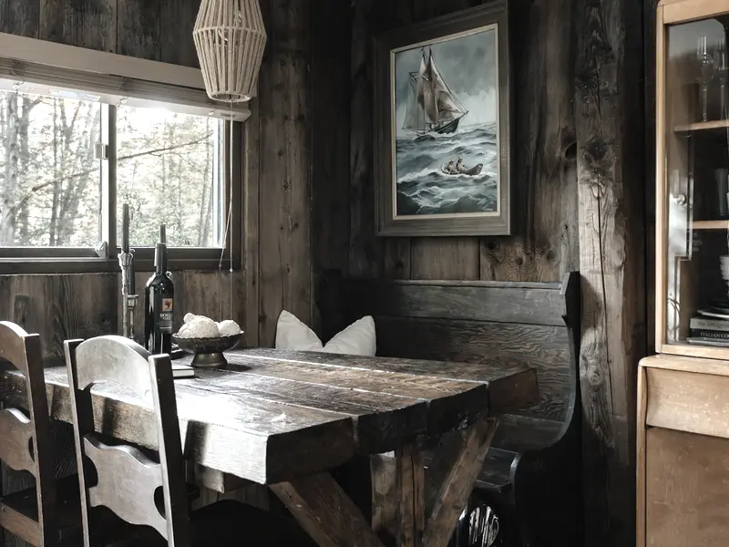 The dining table under the window with high-backed wooden chairs
