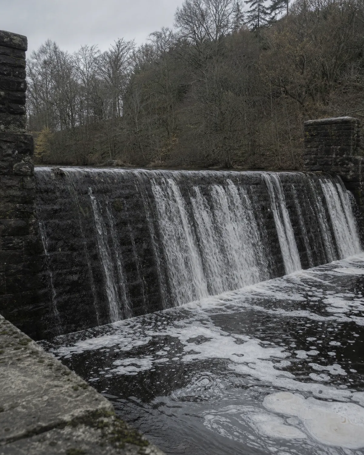 The stone weir at Ashcombe, foam collecting in the pool beneath it.