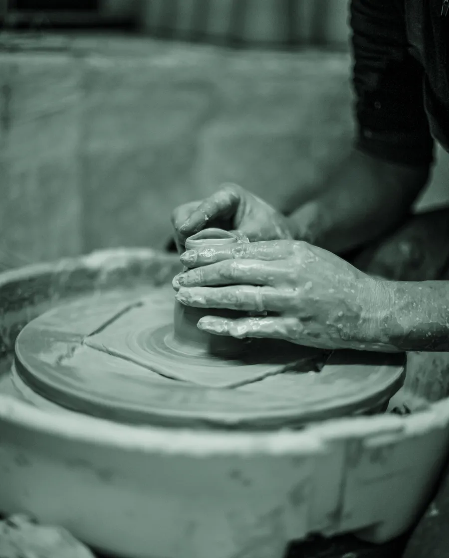 Hands shaping clay on a potter's wheel.