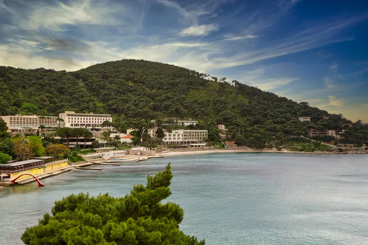 A pine-covered headland above a shallow turquoise bay