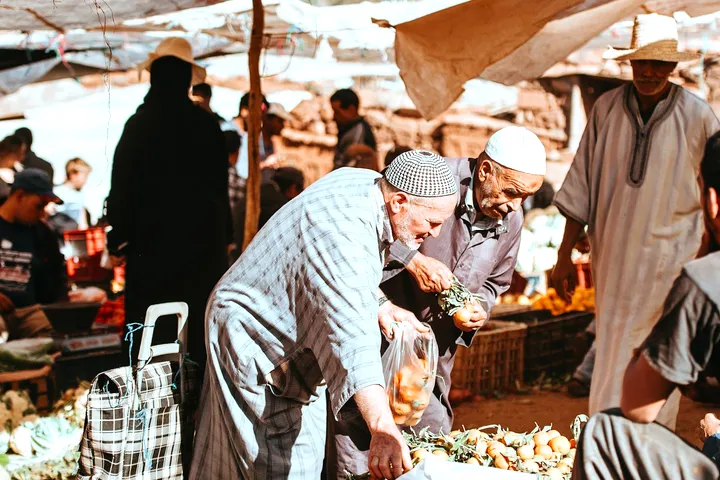 Traders bent over baskets of produce under a market awning