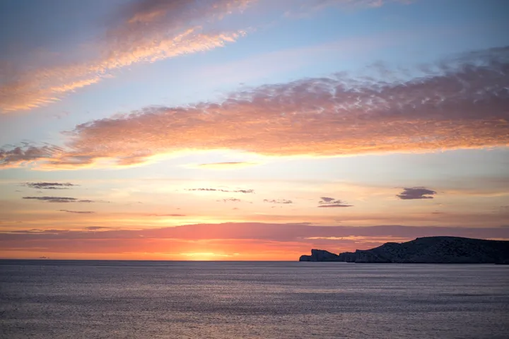 A long band of cloud over open water at the end of the day