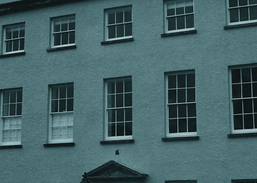 The stone facade of a Georgian terrace house with tall sash windows