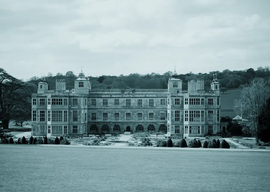 A long stone manor house set behind a wide lawn