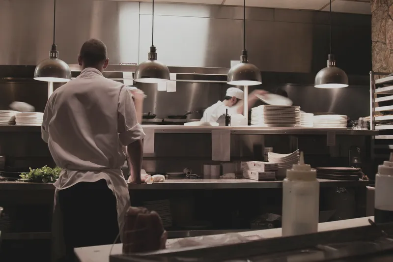 Chefs working the pass in a dim kitchen at night