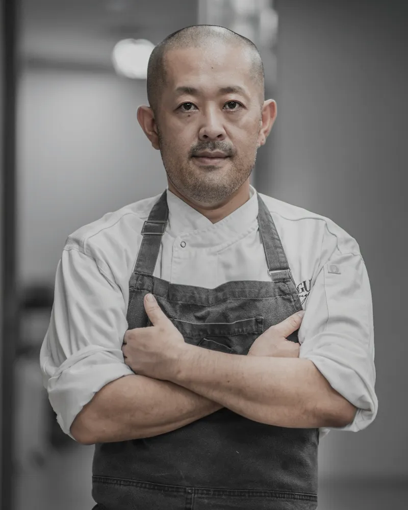 Portrait of the chef in whites and an apron, arms folded