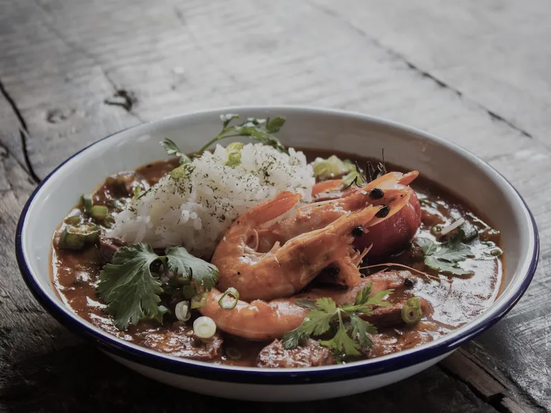 A shellfish broth in a deep bowl with rice and herbs