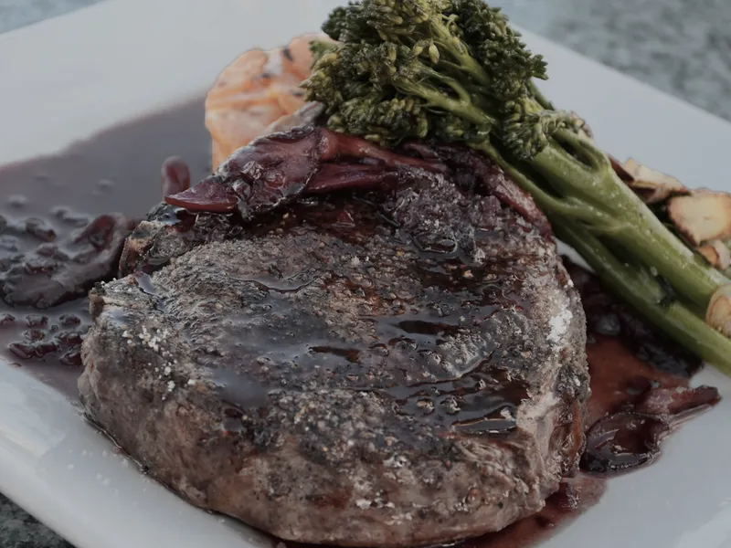A dark seared cut of meat glazed with jus