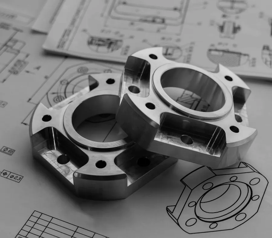 Two machined aluminium hub flanges resting on the general arrangement drawings they were cut from.