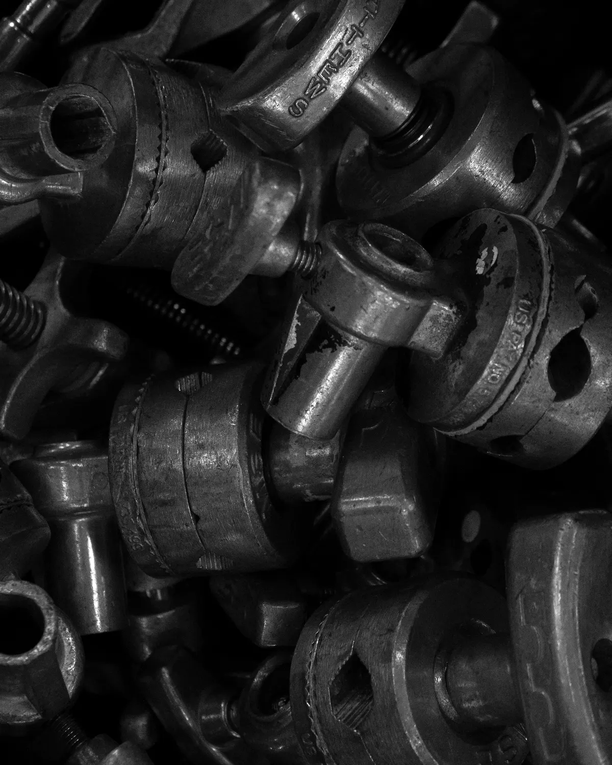 A close, dark pile of cast steel fittings: threads, hexes and bores.