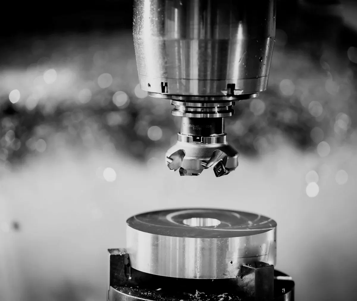 A face mill cutting an aluminium disc clamped in a machine vice, chips still on the table.