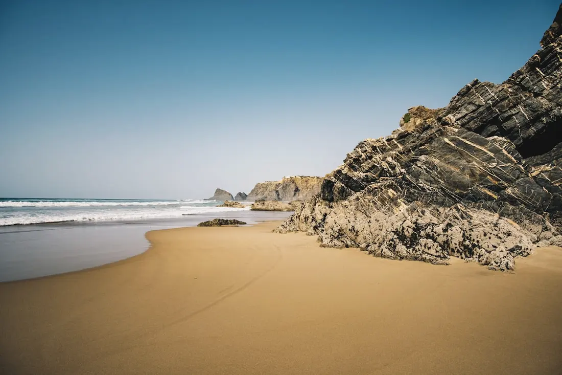 The wide sand and dark rock stacks of the beach at Odeceixe