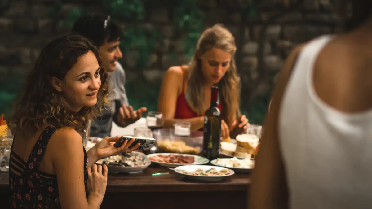 A small group over a long welcome dinner, wine and shared plates, warm evening light against a stone wall