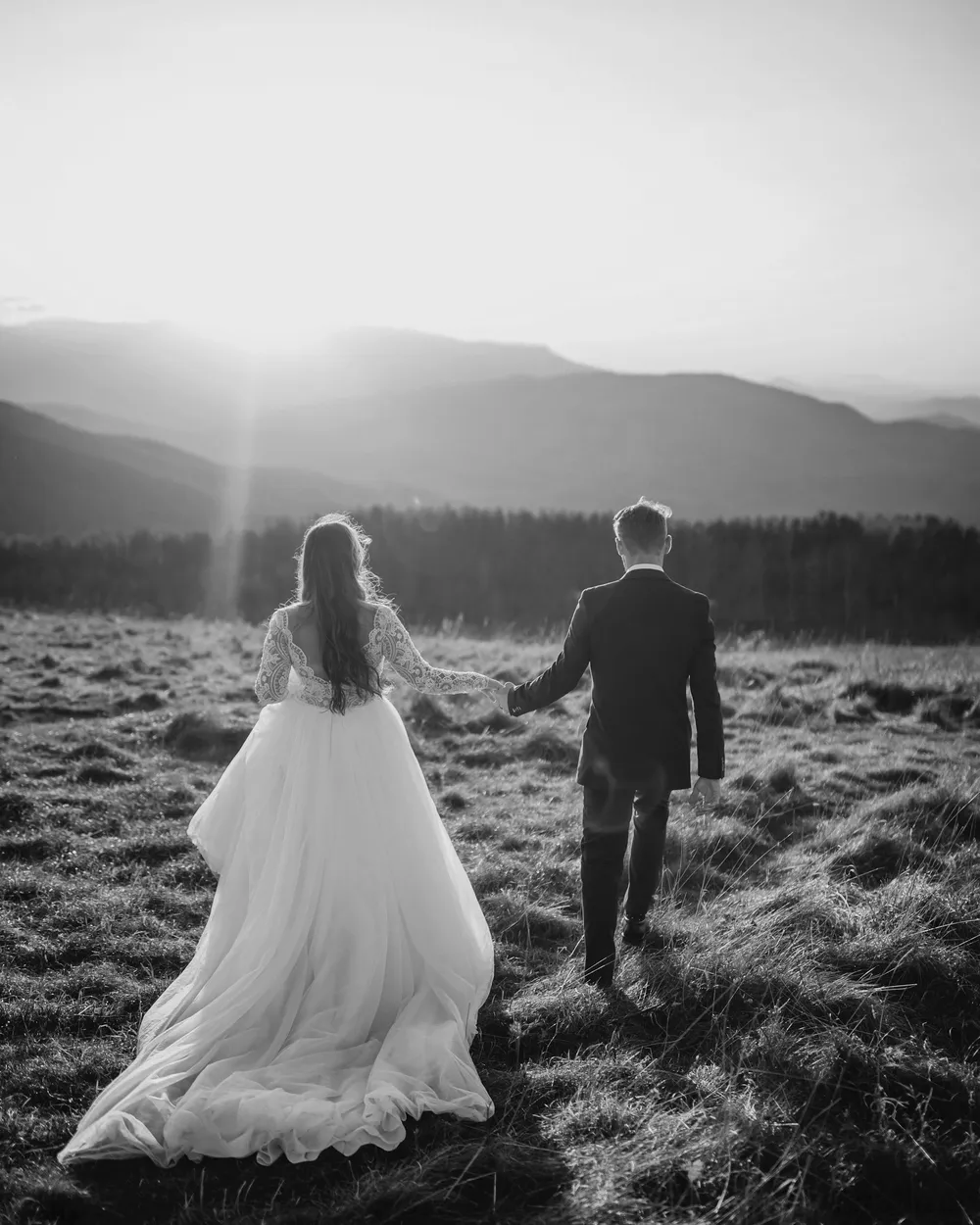 Martha and Elliot walking hand in hand across a hillside at sunset